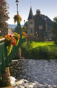 The River Earn flows underneath a flower decorated bridge in Comrie, Scotland